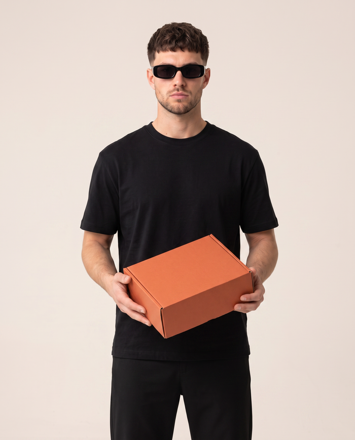 Skrivnostna škatla Creed Fashion — model drži paket s kratkimi majicami